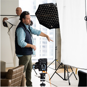 A man is positioned in front of a white backdrop