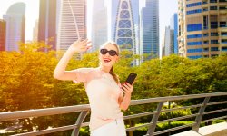 cheerful-woman-with-red-lips-raises-her-hand-up-while-she-stands-bridge-before-skyscrapers (1)