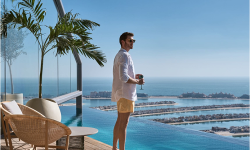 A man on a balcony looks out over the ocean